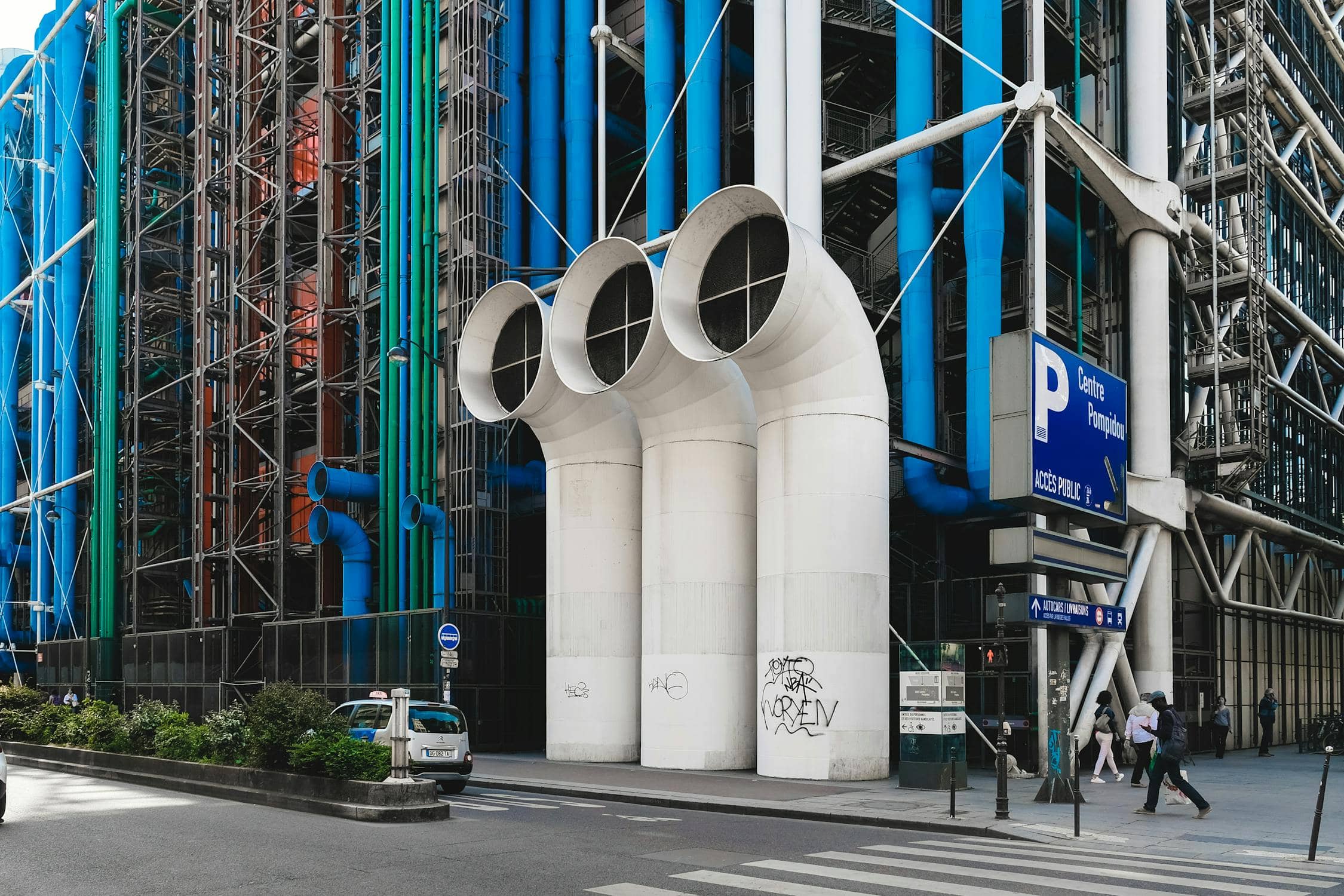 Blue, green, white pipes lining building facade